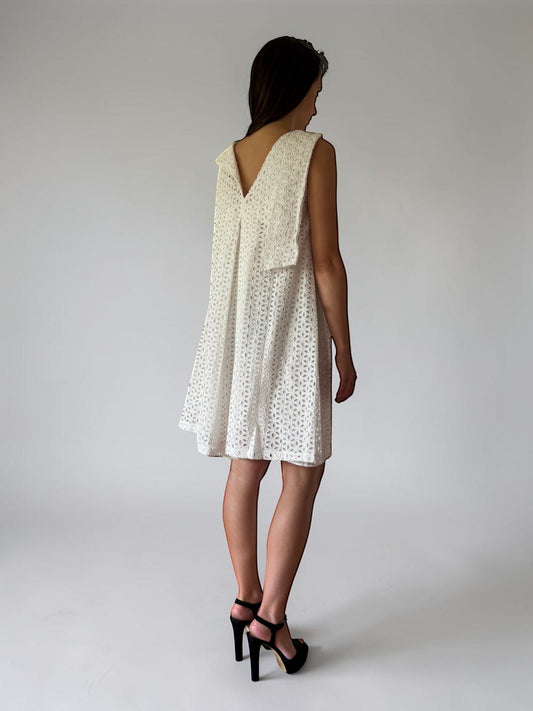 Abito corto Invogue Again in pizzo San Gallo bianco con scollo a V sulla schiena, indossato da una modella