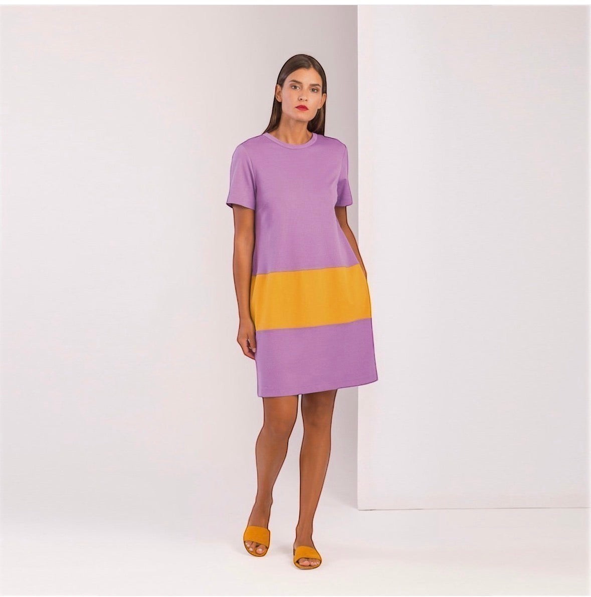 Modella indossa l'abito GIOTTA Sciacca di Invogue Again, vestito corto viola e giallo con tasche laterali.