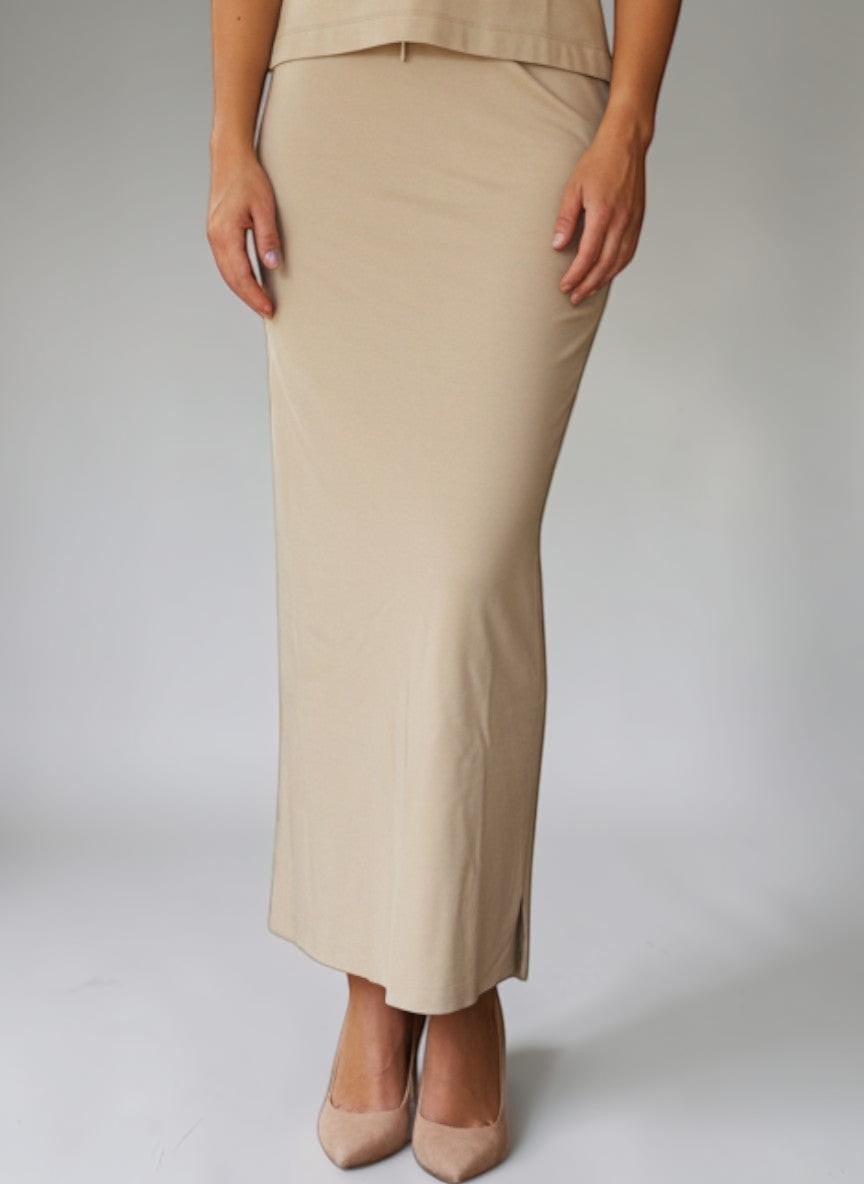 Modella indossa gonna lunga beige Invogue Again abbinata a top senza maniche con scollo a goccia su sfondo neutro