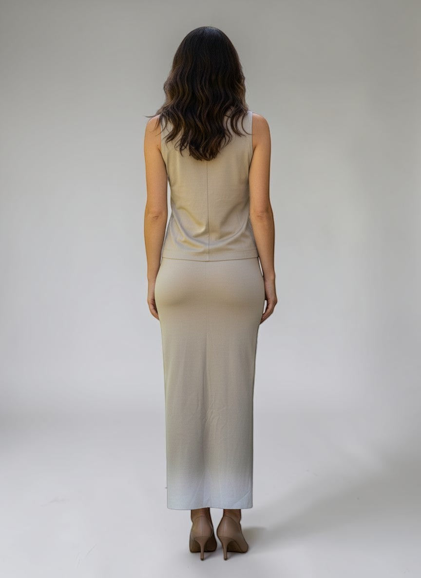 Donna di spalle indossa un completo Invogue Again beige con top smanicato e gonna lunga in un giardino soleggiato