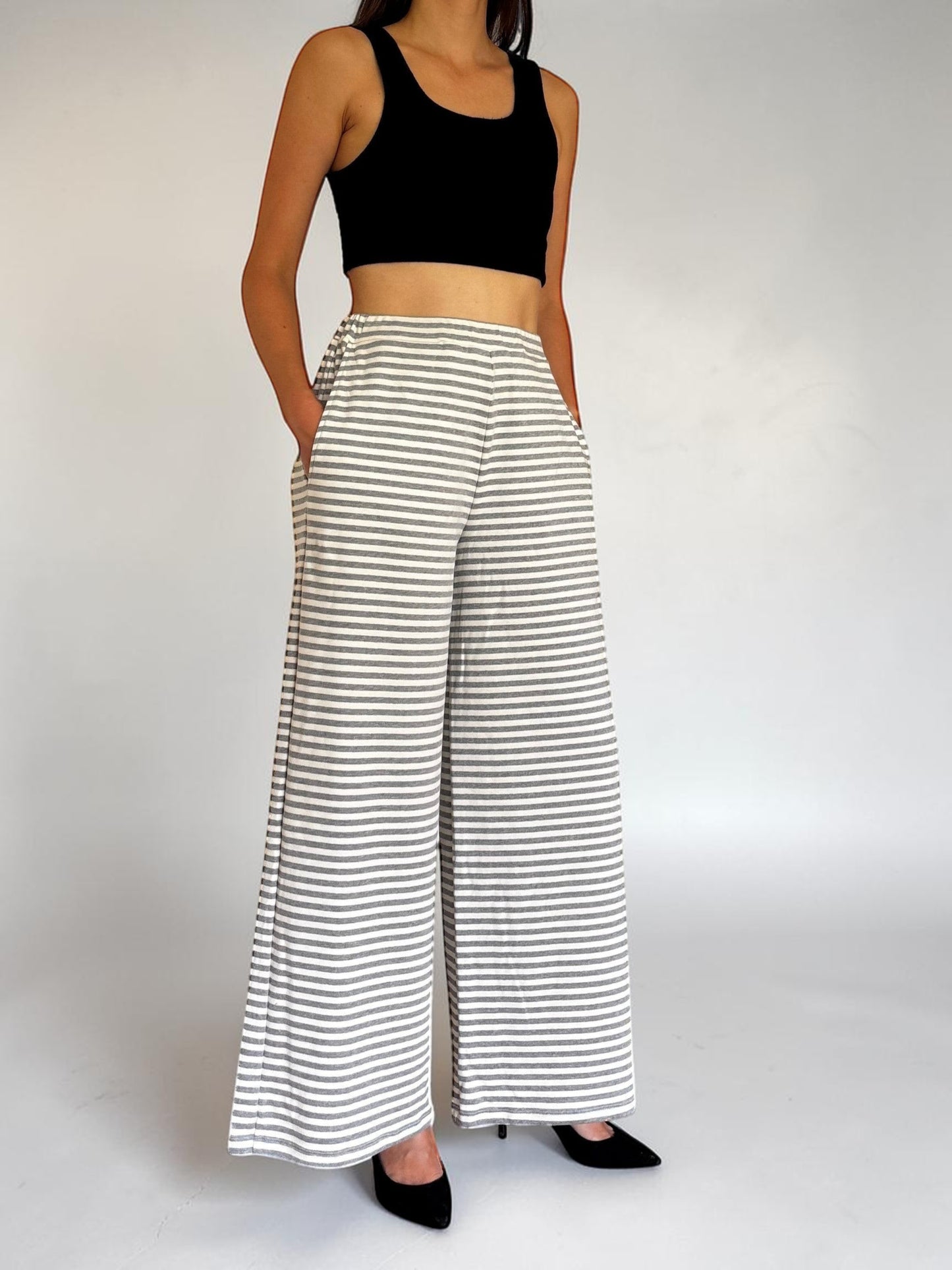Modella indossa pantaloni a gamba larga a righe bianche e grigie Invogue Again con top nero e tacchi