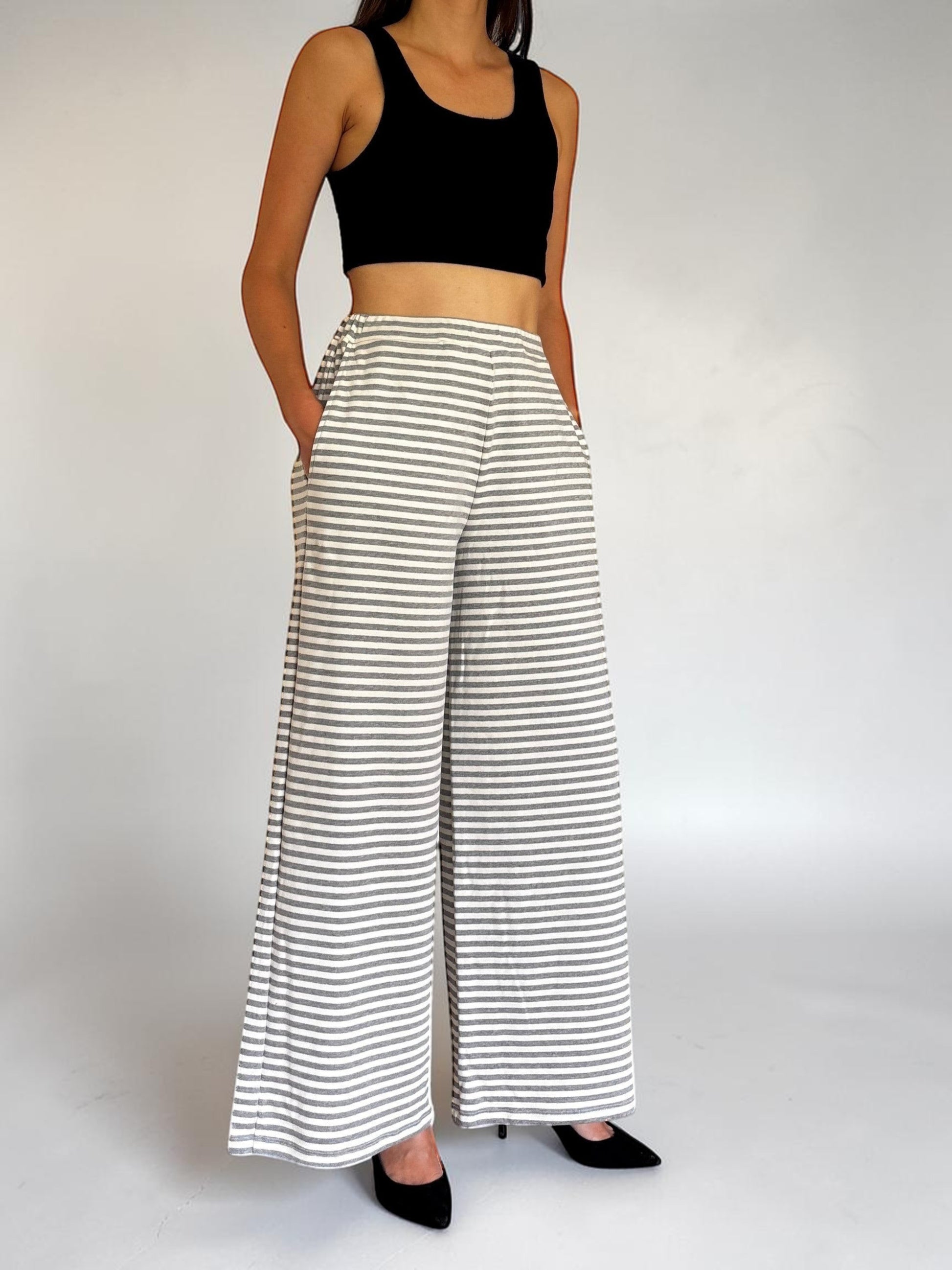 Modella indossa pantaloni a gamba larga a righe bianche e grigie Invogue Again con top nero e tacchi