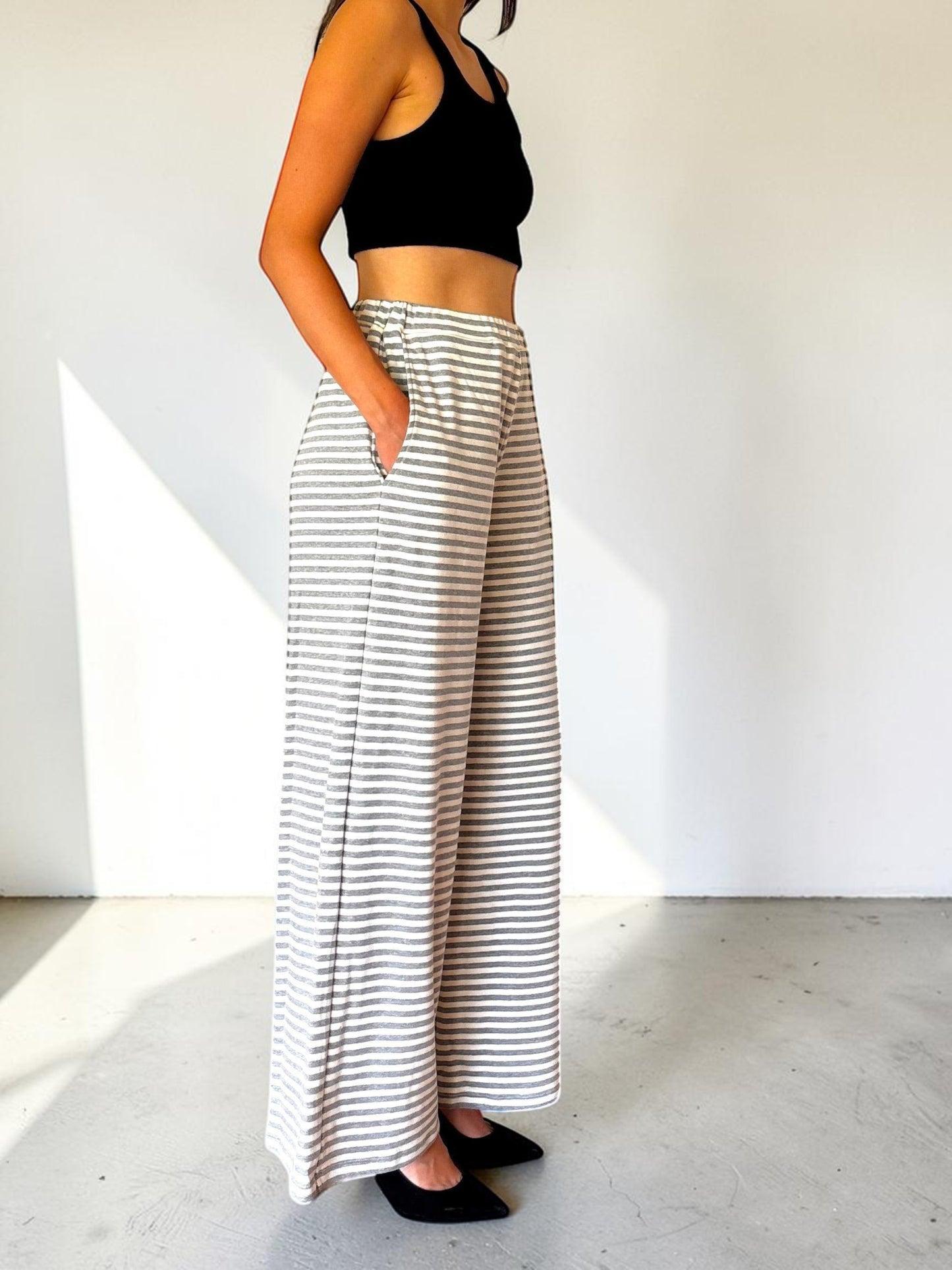 Modella indossa pantaloni a righe bianche e grigie Invogue Again dal taglio ampio e vita alta con tasche laterali