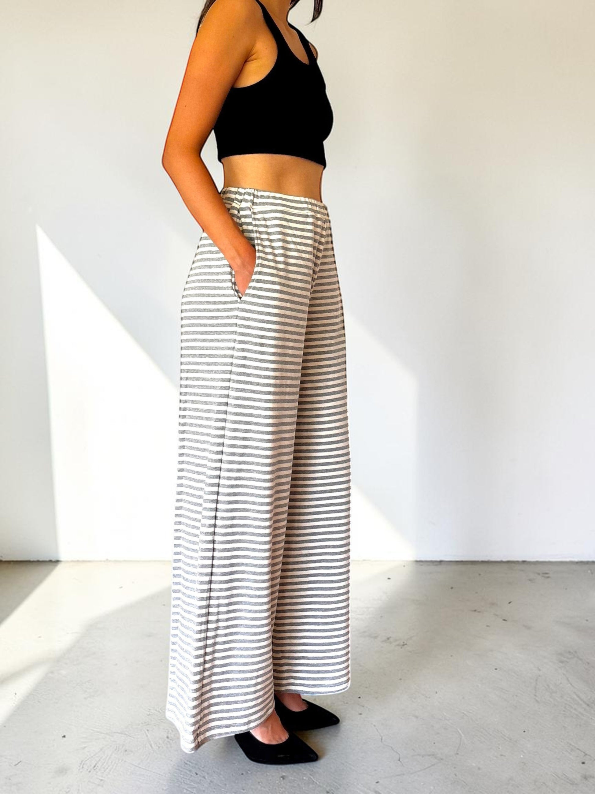 Modella indossa pantaloni a righe bianche e grigie Invogue Again dal taglio ampio e vita alta con tasche laterali