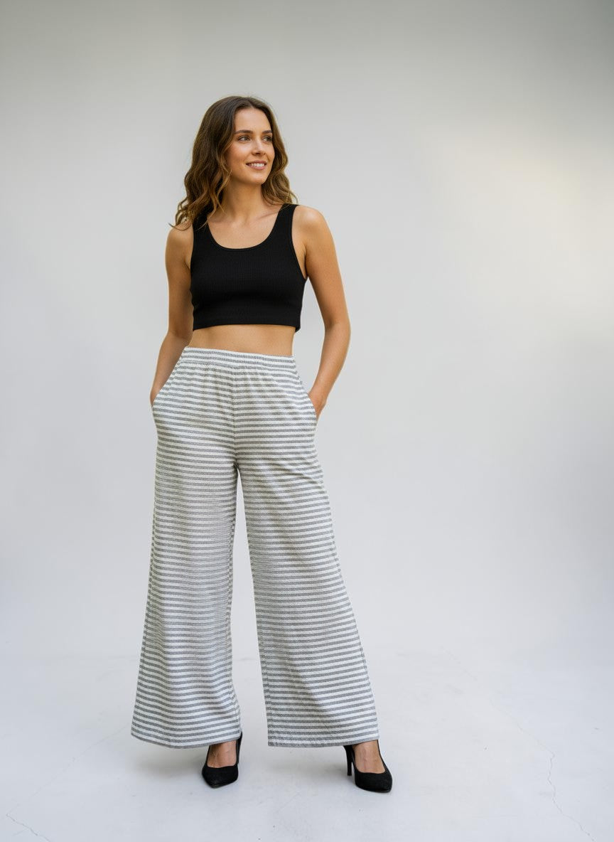 Modella indossa pantaloni a righe bianche e grigie Invogue Again in cotone con vita elastica in un parco cittadino